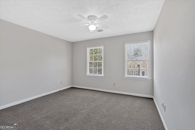 unfurnished room with ceiling fan, a textured ceiling, baseboards, and dark colored carpet