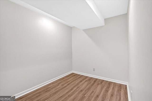 spare room with baseboards and wood finished floors