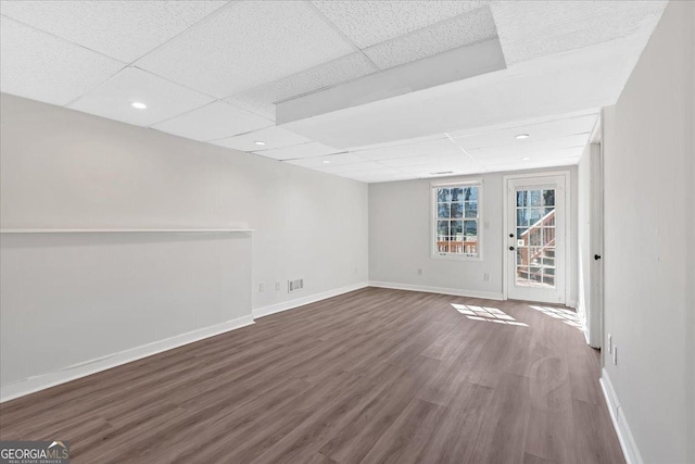 unfurnished room featuring dark wood finished floors, visible vents, baseboards, and a drop ceiling