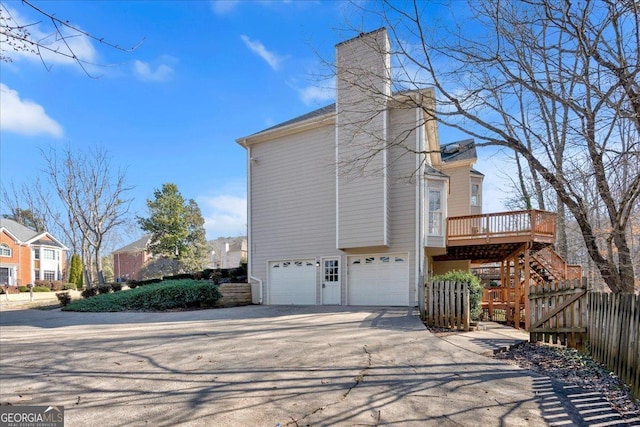 view of property exterior with fence, an attached garage, a chimney, stairs, and concrete driveway