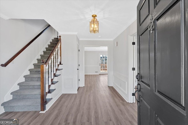 foyer entrance with stairs, wood finished floors, wainscoting, and ornamental molding