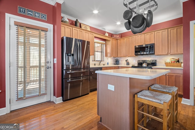 kitchen with backsplash, a kitchen island, crown molding, light countertops, and appliances with stainless steel finishes