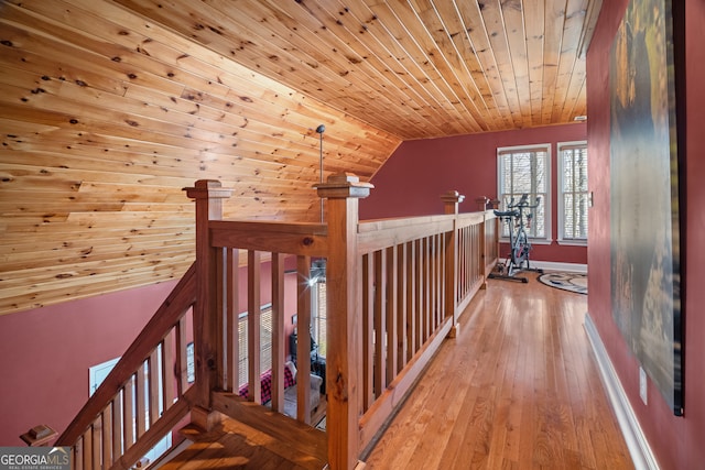 corridor with baseboards, vaulted ceiling, an upstairs landing, wooden ceiling, and hardwood / wood-style flooring