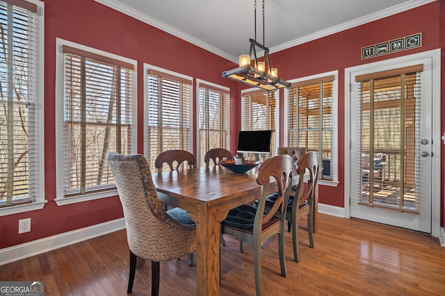 dining area featuring hardwood / wood-style floors, baseboards, a chandelier, and crown molding