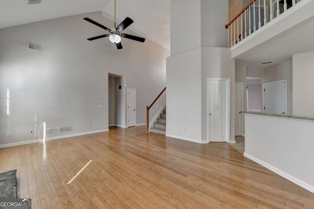 unfurnished living room with stairs, light wood-style flooring, baseboards, and visible vents