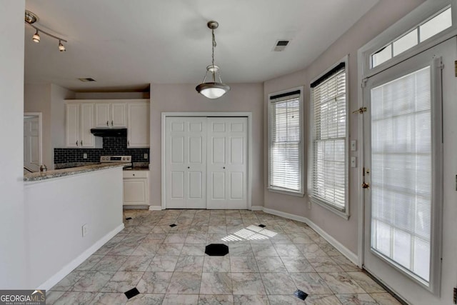 kitchen featuring under cabinet range hood, visible vents, white cabinets, and tasteful backsplash