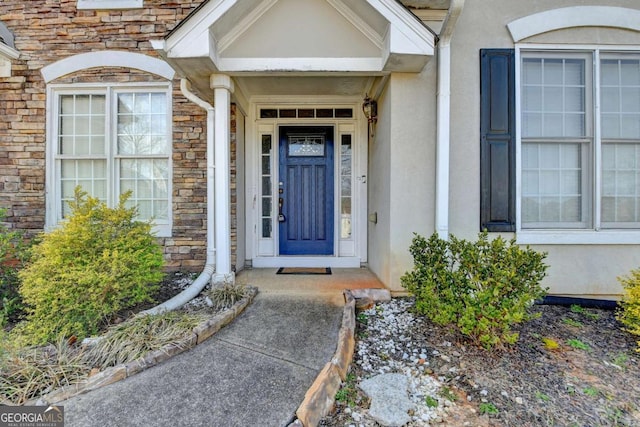 property entrance with stucco siding and stone siding