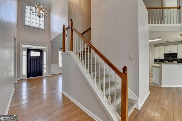 foyer entrance with baseboards, light wood-style floors, and a towering ceiling
