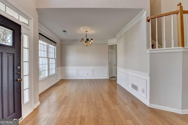 foyer entrance featuring ornamental molding, a notable chandelier, visible vents, and light wood-type flooring