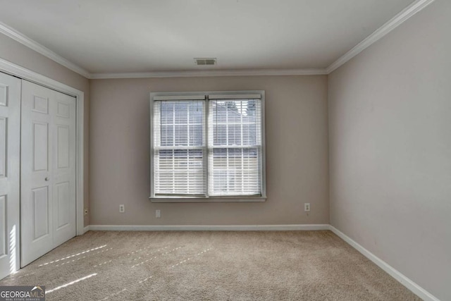 unfurnished bedroom with visible vents, carpet flooring, crown molding, and baseboards