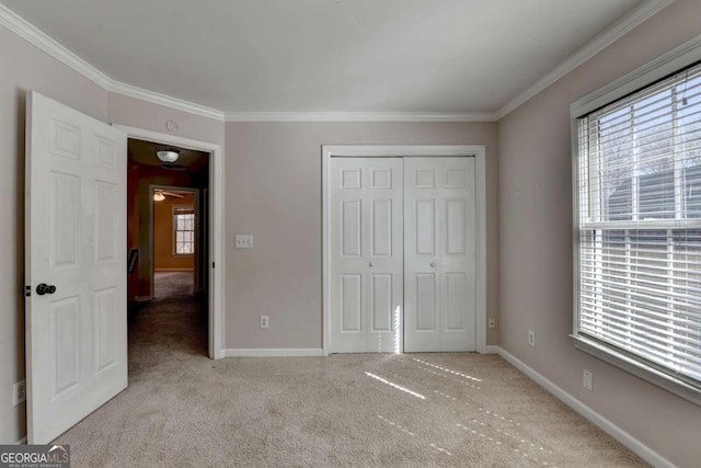 unfurnished bedroom with a closet, baseboards, carpet, and ornamental molding