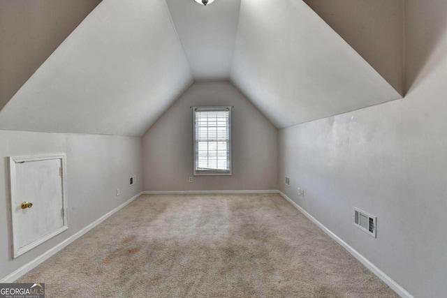 additional living space with visible vents, baseboards, carpet flooring, and vaulted ceiling