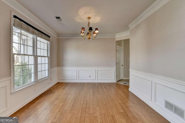 unfurnished dining area with light wood finished floors, visible vents, crown molding, and an inviting chandelier