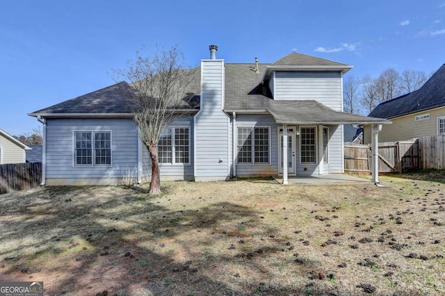 back of house with a patio area, fence, and a chimney