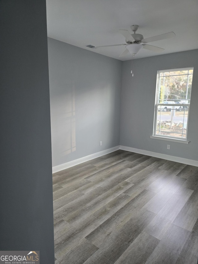 unfurnished room with visible vents, ceiling fan, baseboards, and wood finished floors