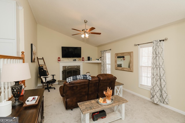 living area with light carpet, lofted ceiling, a tiled fireplace, baseboards, and ceiling fan