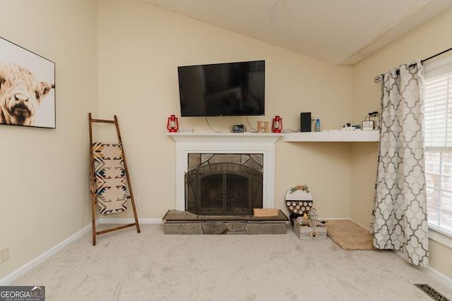 living area with visible vents, baseboards, lofted ceiling, carpet floors, and a stone fireplace