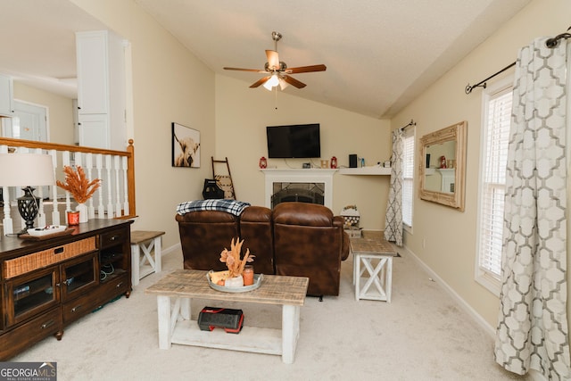 living room featuring baseboards, ceiling fan, lofted ceiling, carpet flooring, and a fireplace