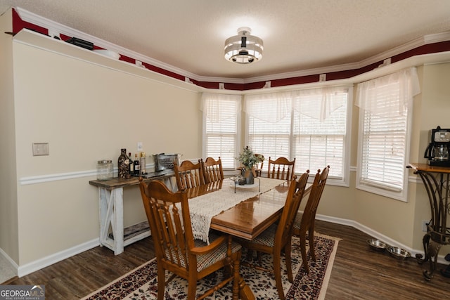 dining room featuring a textured ceiling, wood finished floors, baseboards, and ornamental molding