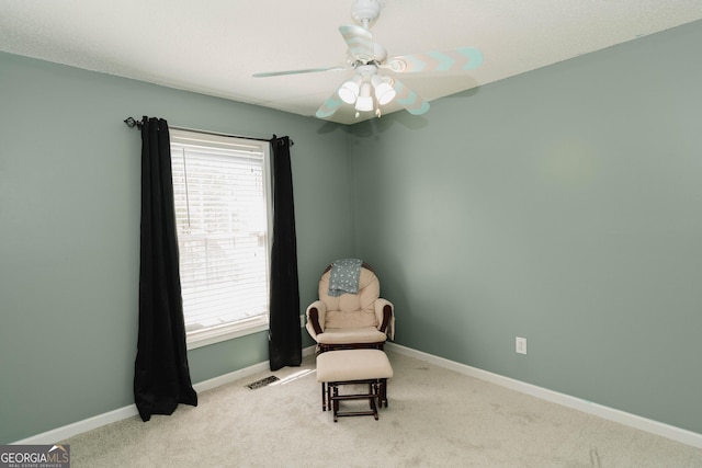 living area featuring baseboards, carpet floors, visible vents, and ceiling fan