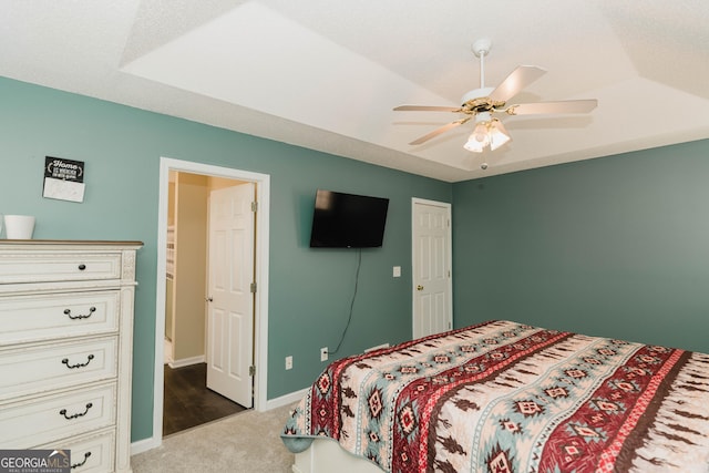 bedroom featuring a tray ceiling, baseboards, carpet floors, and ceiling fan