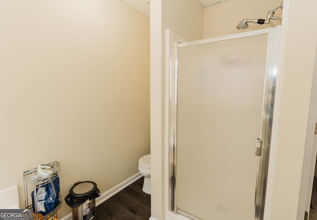 full bath with baseboards, toilet, wood finished floors, and a shower stall