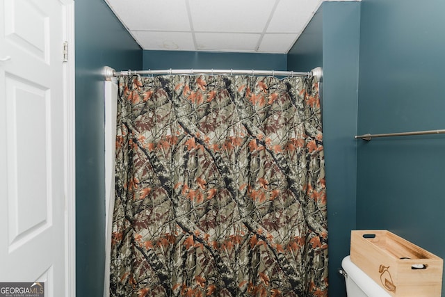 bathroom featuring curtained shower, a paneled ceiling, and toilet