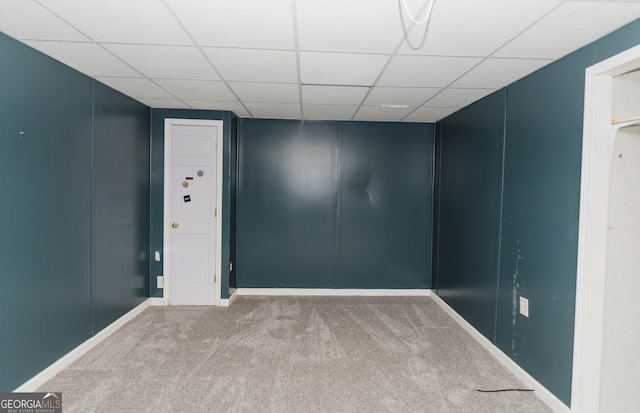 spare room featuring a drop ceiling, carpet flooring, and a decorative wall