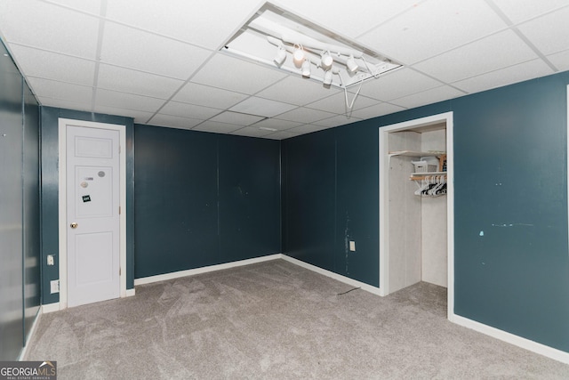 interior space with a paneled ceiling, carpet floors, and baseboards