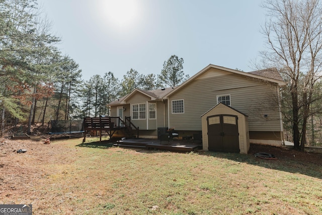 rear view of property with a trampoline, a shed, a lawn, an outdoor structure, and a deck