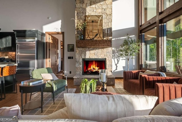 living area with wood finished floors, a fireplace, and a towering ceiling