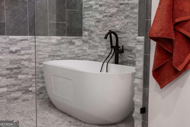 bathroom with tile walls and a freestanding tub