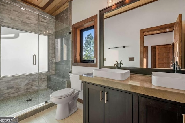 full bathroom featuring double vanity, a shower stall, toilet, and a sink