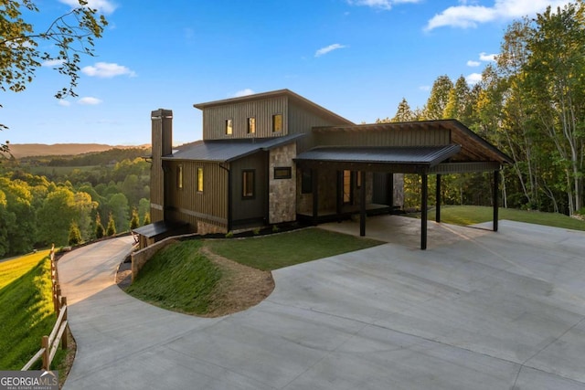 exterior space featuring metal roof, stone siding, a chimney, and a front lawn