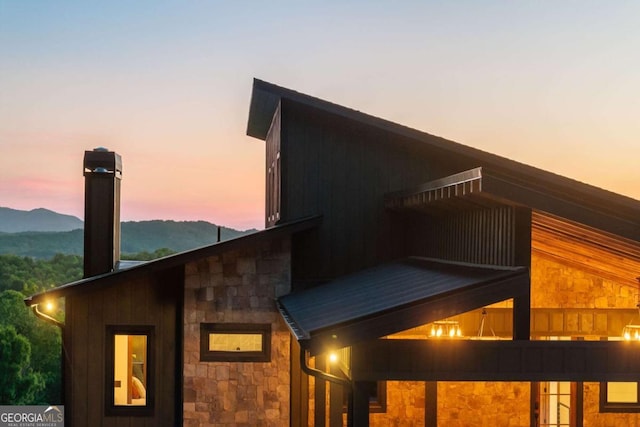 property exterior at dusk featuring stone siding