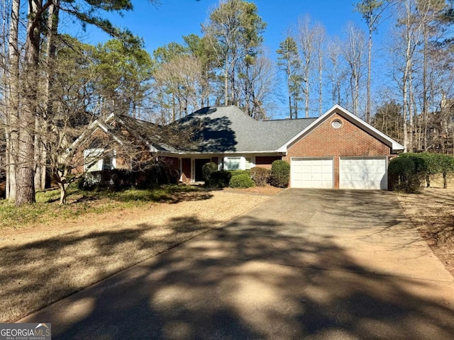 single story home featuring brick siding, an attached garage, and driveway