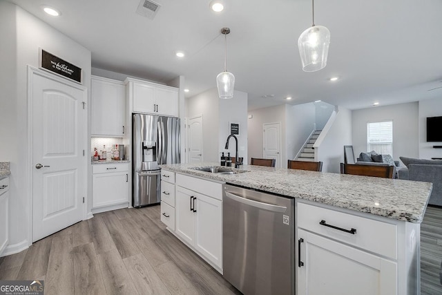 kitchen featuring visible vents, backsplash, appliances with stainless steel finishes, light wood-style floors, and a sink