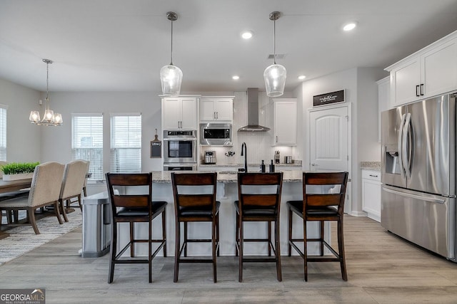 kitchen featuring decorative backsplash, appliances with stainless steel finishes, wall chimney exhaust hood, and white cabinets