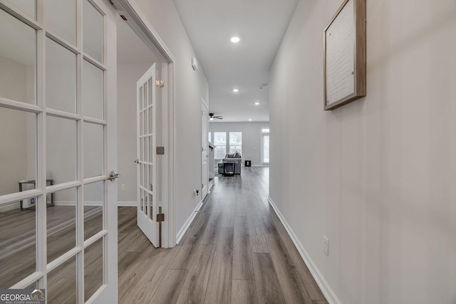 hallway featuring wood finished floors, recessed lighting, french doors, and baseboards