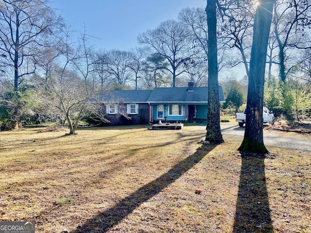 view of front of house with brick siding, a front lawn, and a chimney