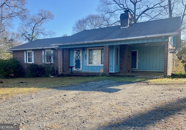 single story home with driveway, brick siding, a chimney, and a shingled roof