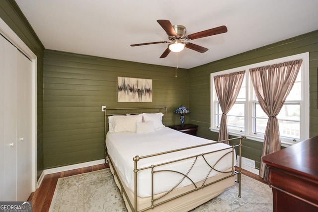 bedroom featuring a closet, a ceiling fan, baseboards, and wood finished floors