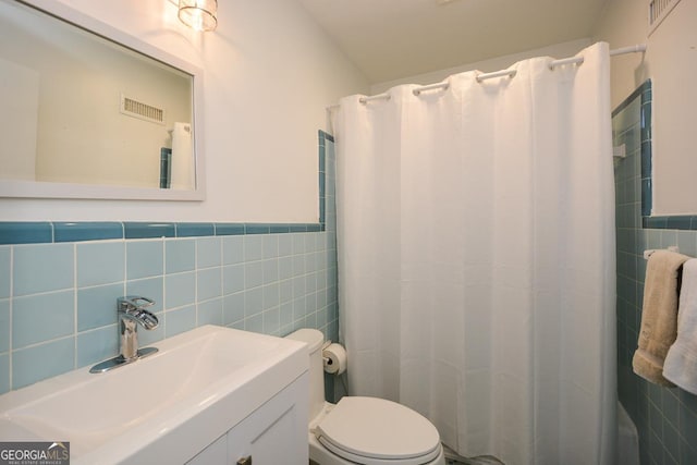 bathroom with tile walls, toilet, and visible vents