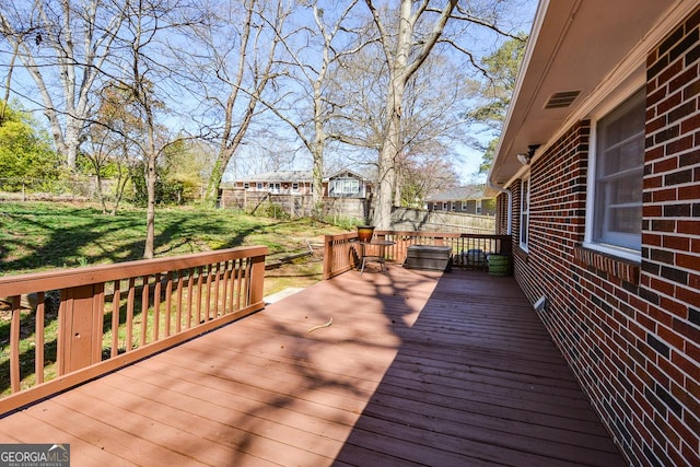 wooden terrace featuring a lawn and fence