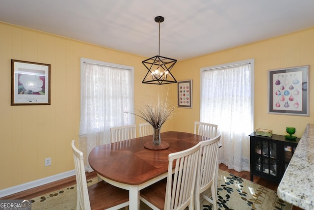 dining space featuring baseboards, an inviting chandelier, and wood finished floors