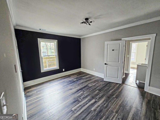 unfurnished bedroom with dark wood-type flooring, visible vents, baseboards, and ornamental molding