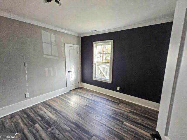 empty room with visible vents, baseboards, dark wood-type flooring, and crown molding