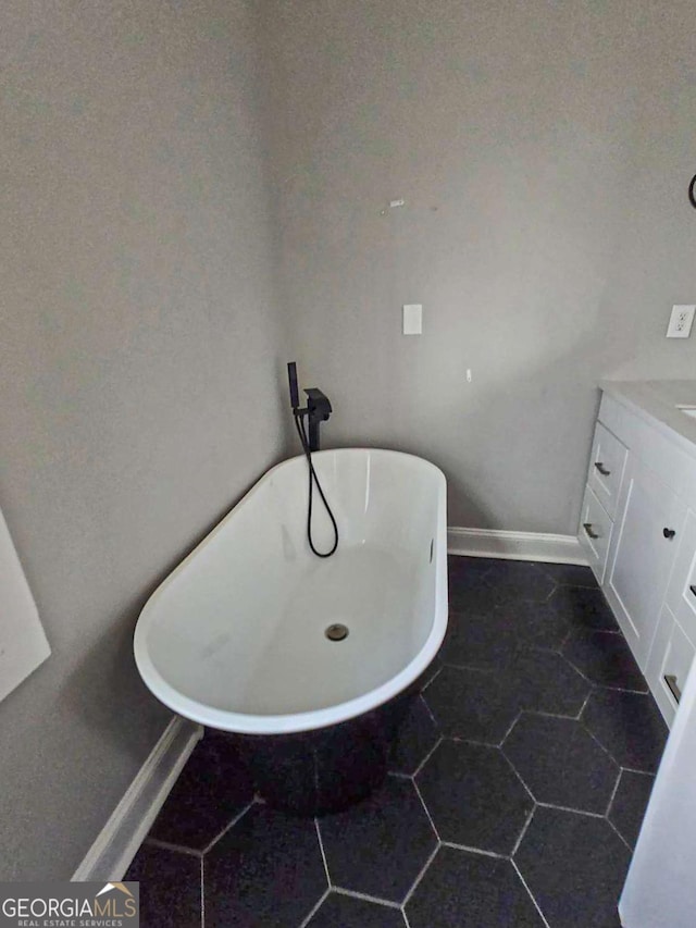 bathroom featuring baseboards, a freestanding bath, and vanity