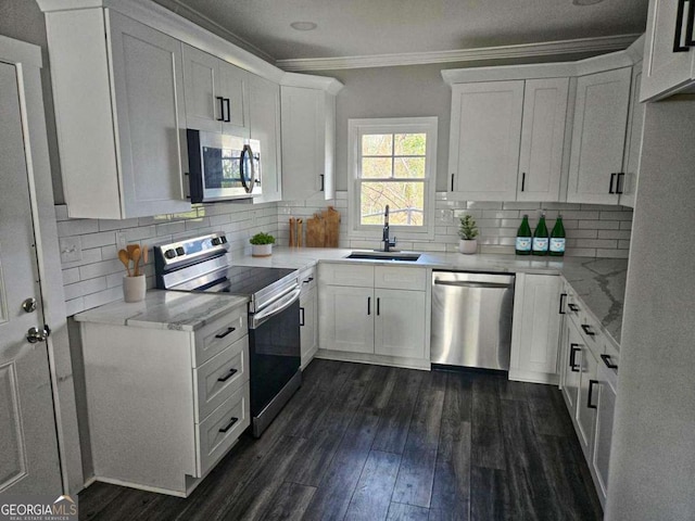 kitchen featuring crown molding, dark wood-style floors, white cabinets, stainless steel appliances, and a sink