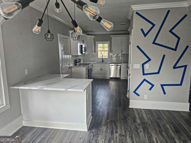 kitchen with a peninsula, a sink, ornamental molding, stainless steel appliances, and tasteful backsplash